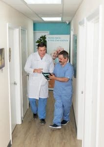 Two men standing in a hallway discussing non-surgical pain treatment.