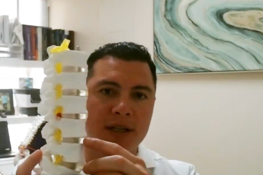 A man holding a model of a spine.