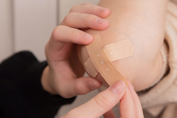 A person putting a band aid on their elbow.