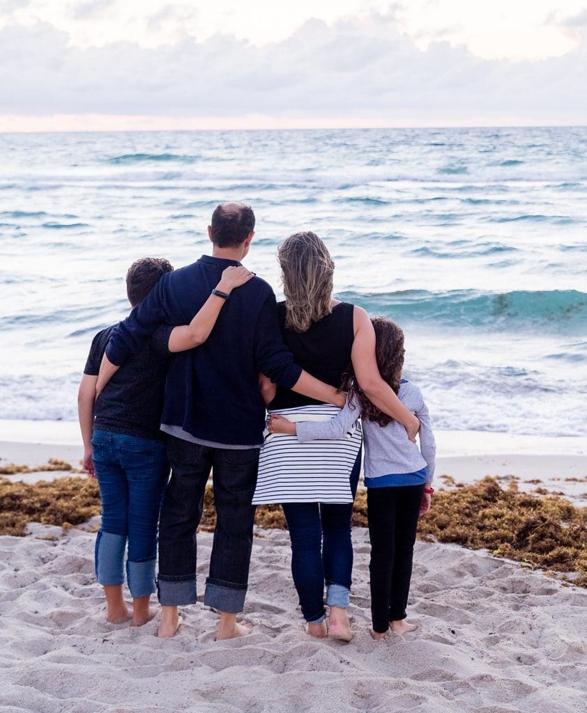A family is standing on the beach in front of the ocean.