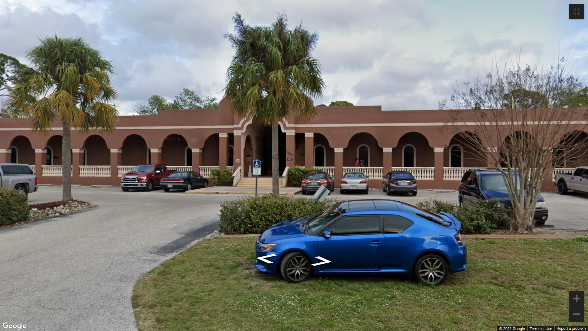 A blue car parked in front of a building.