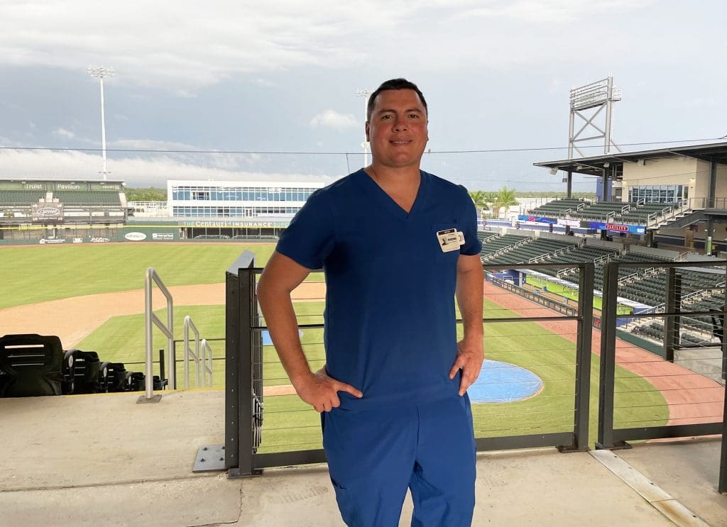 A man standing in front of a baseball field.