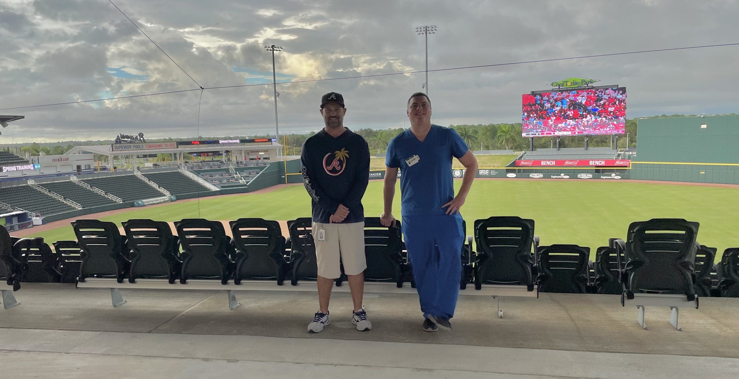 Two men standing in front of a baseball stadium.