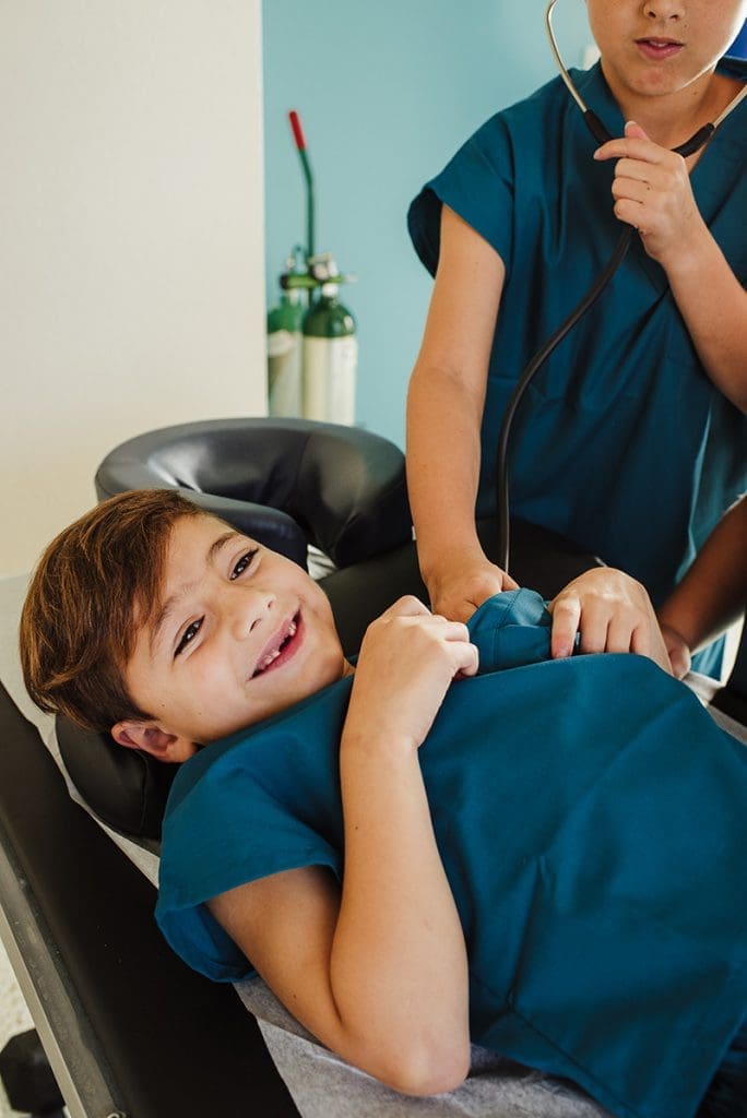 A boy lying on a chair with a stethoscope.