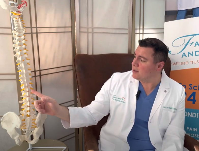 A man in a white coat is pointing to a skeleton.