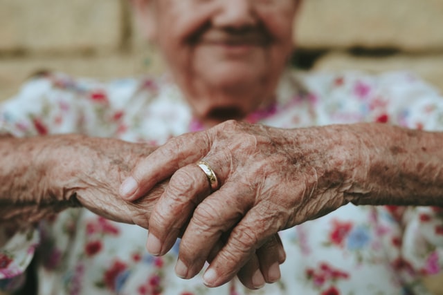 An elderly woman's hands are holding a ring.