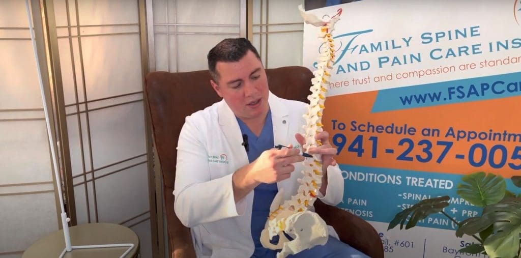 A man in a white coat holding a skeleton model.