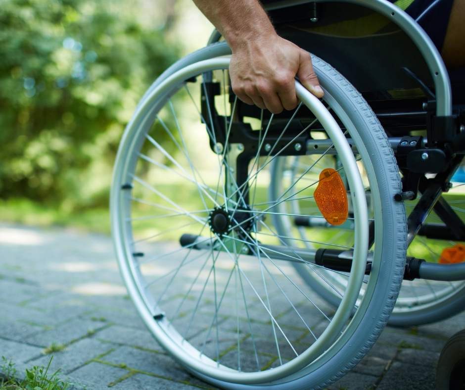 A man in a wheelchair pushing a wheel.