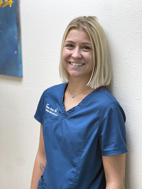 A woman in blue scrubs smiling.